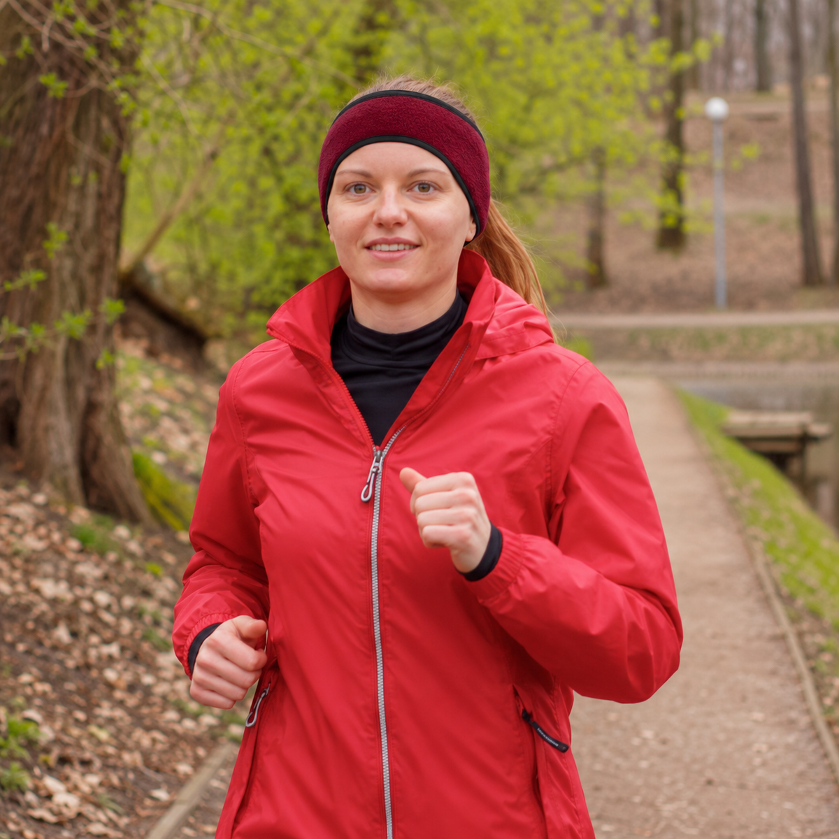 Styled photograph of a runner wearing the burgundy Cold Pace headband with her ponytail above the band