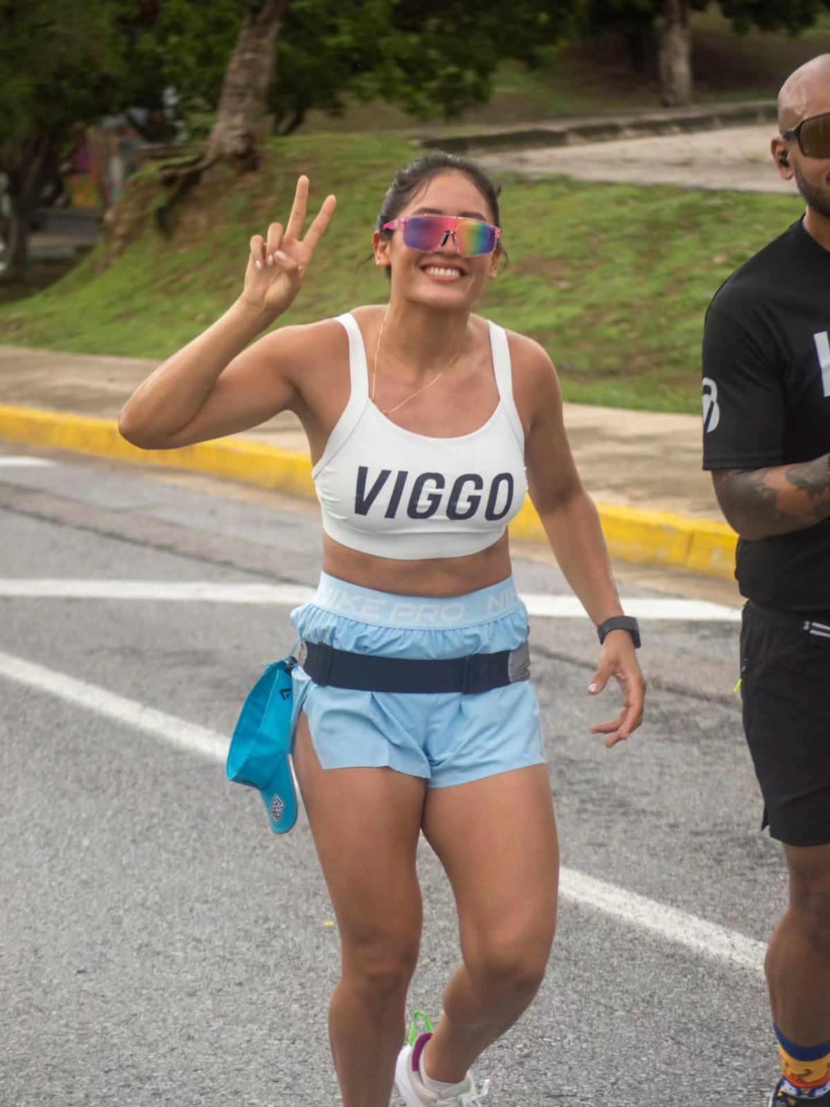Race participant waving while wearing pink mirrored shield sunglasses