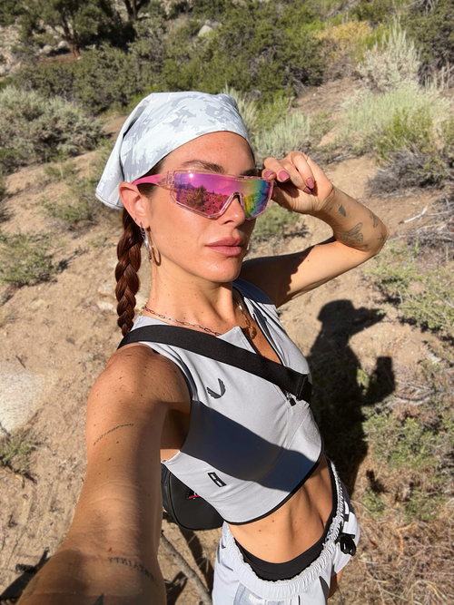 Woman on a trail wearing pink mirrored shield sunglasses