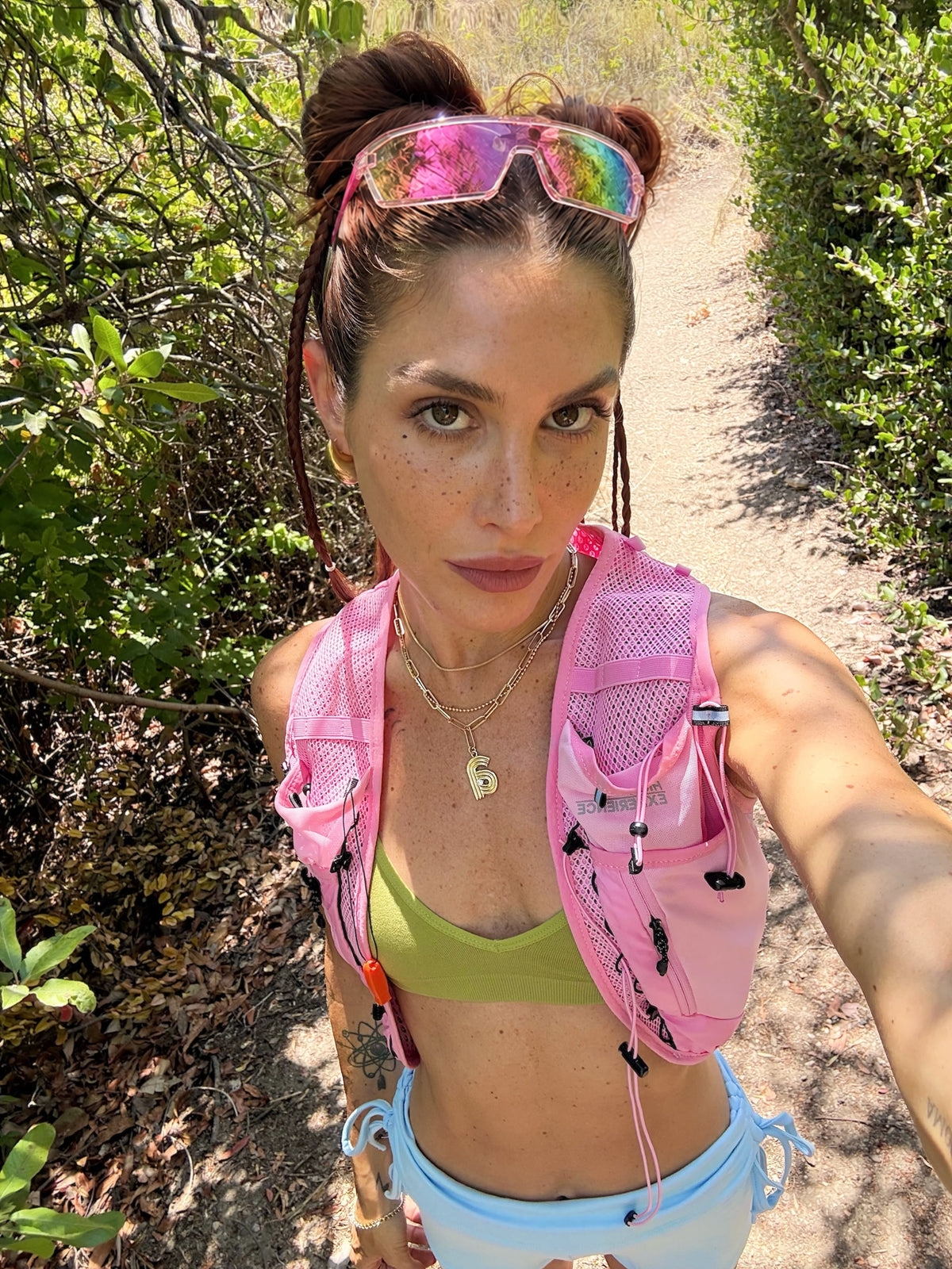 Trail runner in a pink vest with pink shield sunglasses on her head